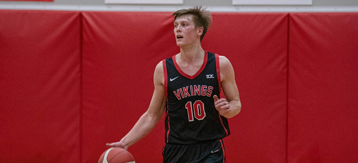 A Vikings men's basketball team member dribbling a basketball.
