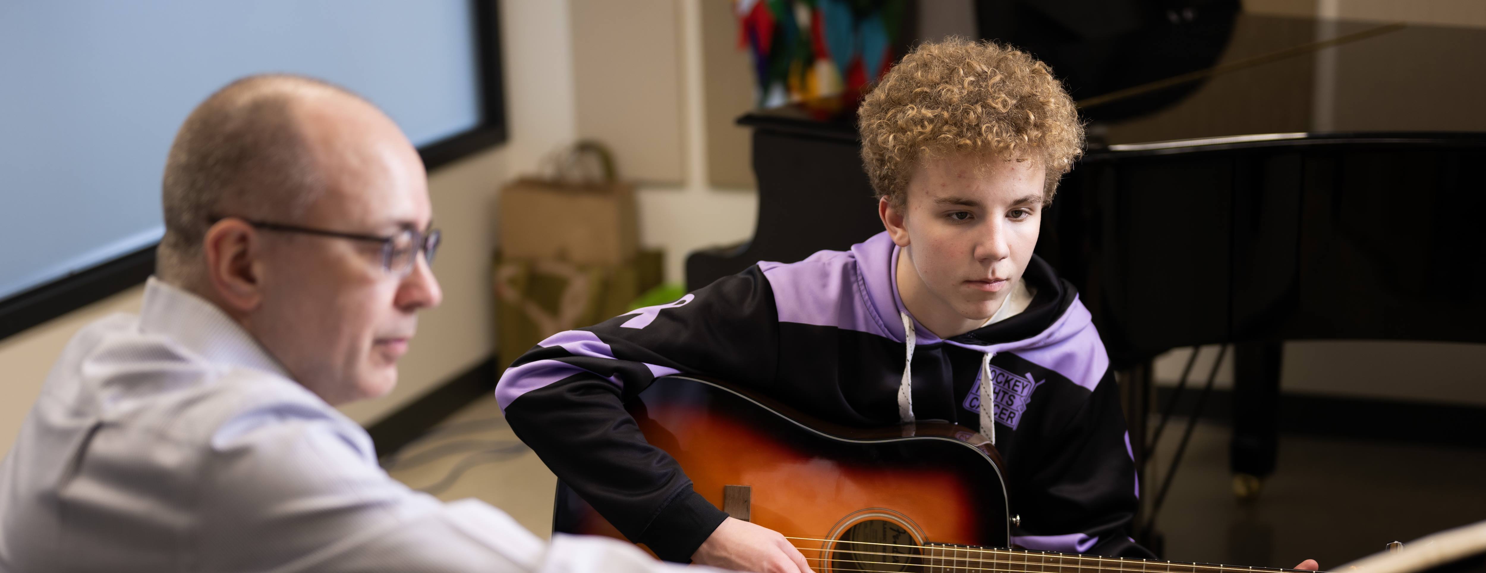 Teacher instructing a student with a guitar