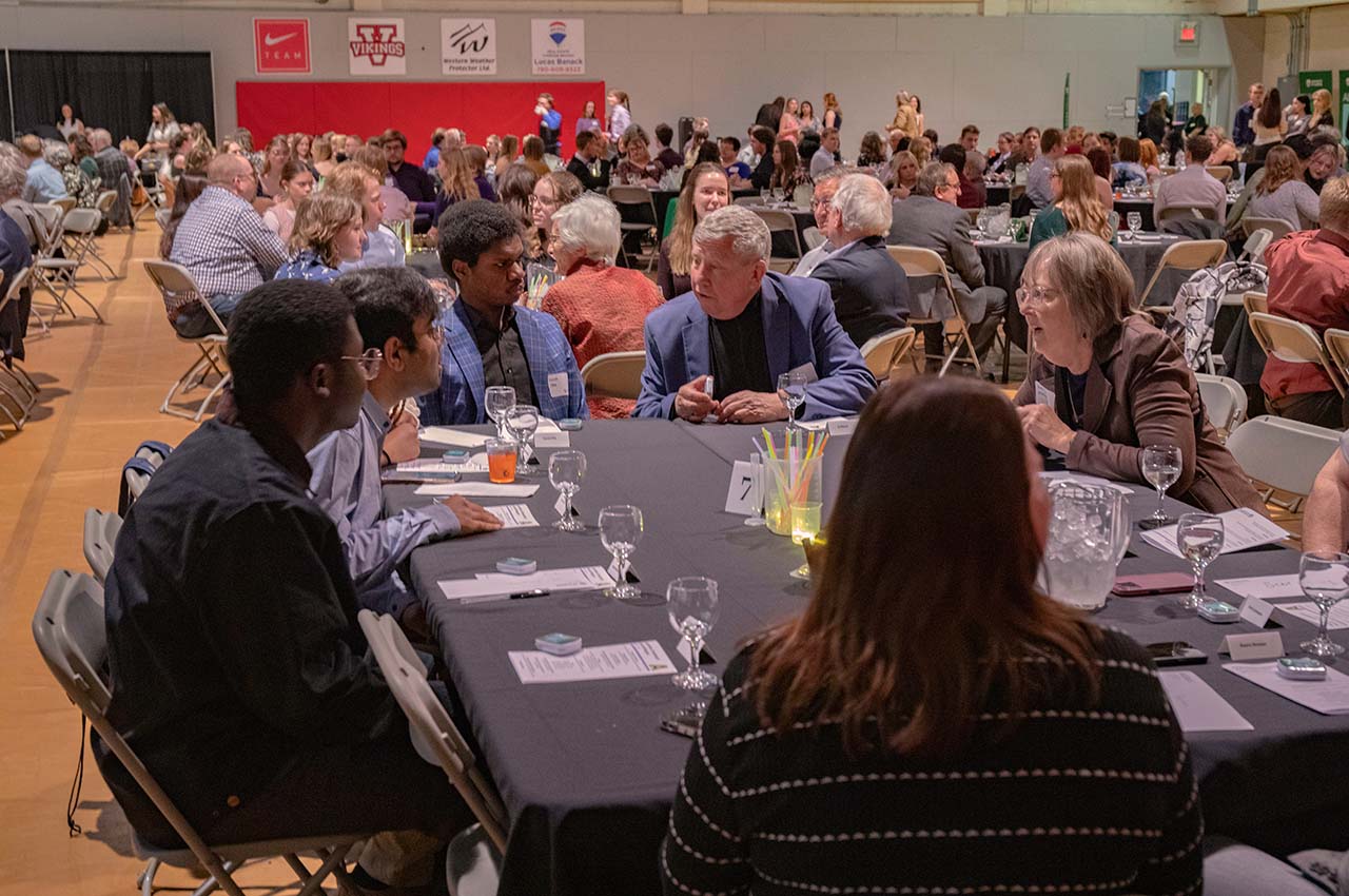 People sitting at tables in the gymnasium.