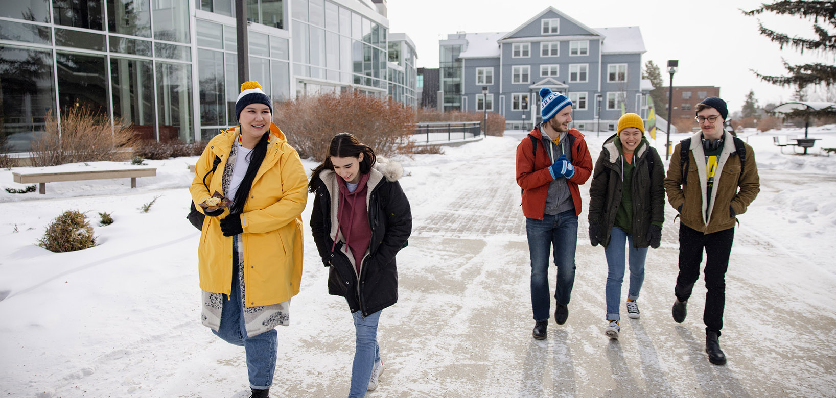 Students walking across a snowy Augustana Campus while wearing winter clothing.