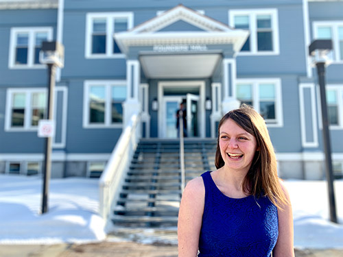 A photo of Mary Cairns sitting in front of Founders' Hall