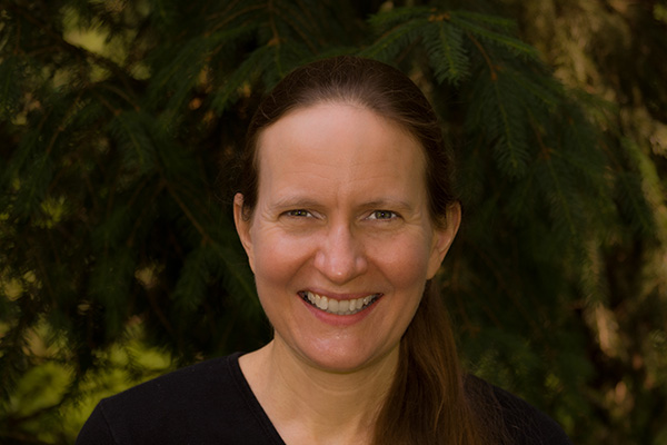Ingrid Urberg smiling at the camera. She is wearing a black shirt and her hair is pulled back.