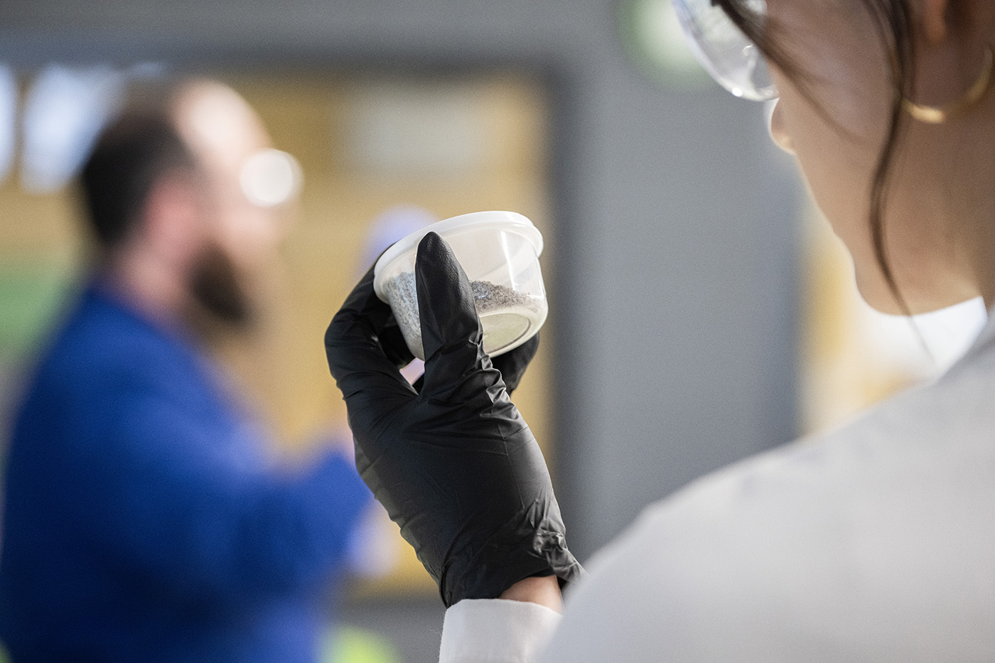 Student inspecting a containers contents in a lab.