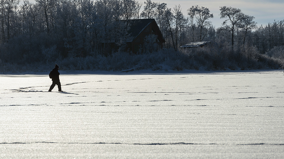 A student walking through a snowy landscape using snowshoes.