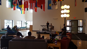 A few people gathered around a musical duo on a low stage