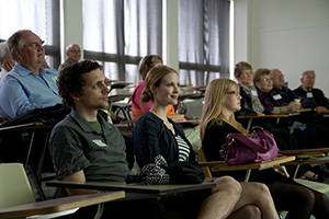 A group of people in tiered desks watching a presentation