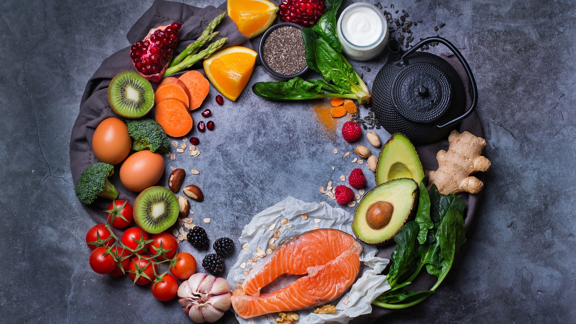 Healthy food ingredients displayed in a circle on a dark grey background