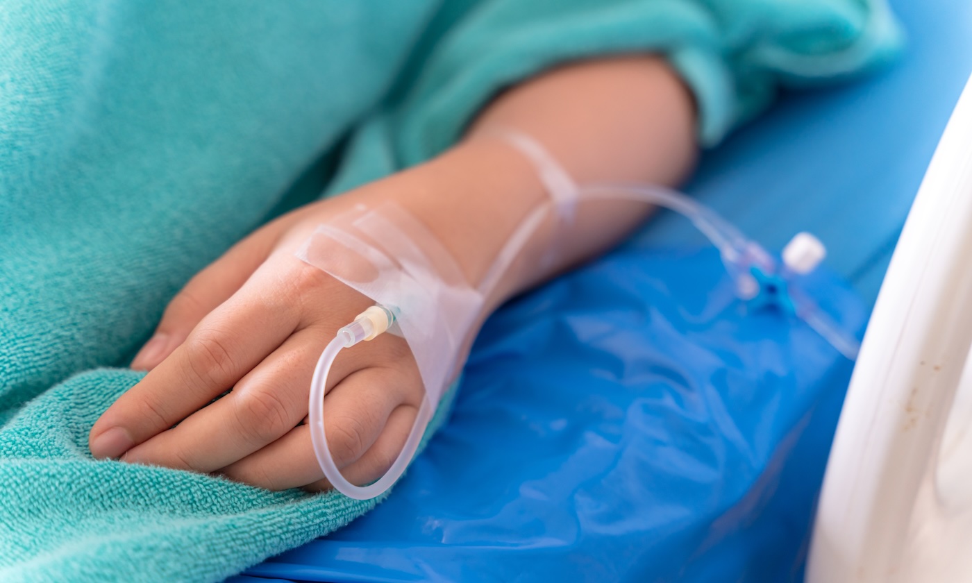 Hand with intravenous on a hospital bed