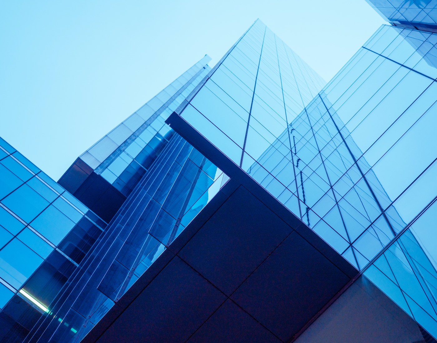 Looking up at the sky through skyscrapers reflecting the blue of the sky