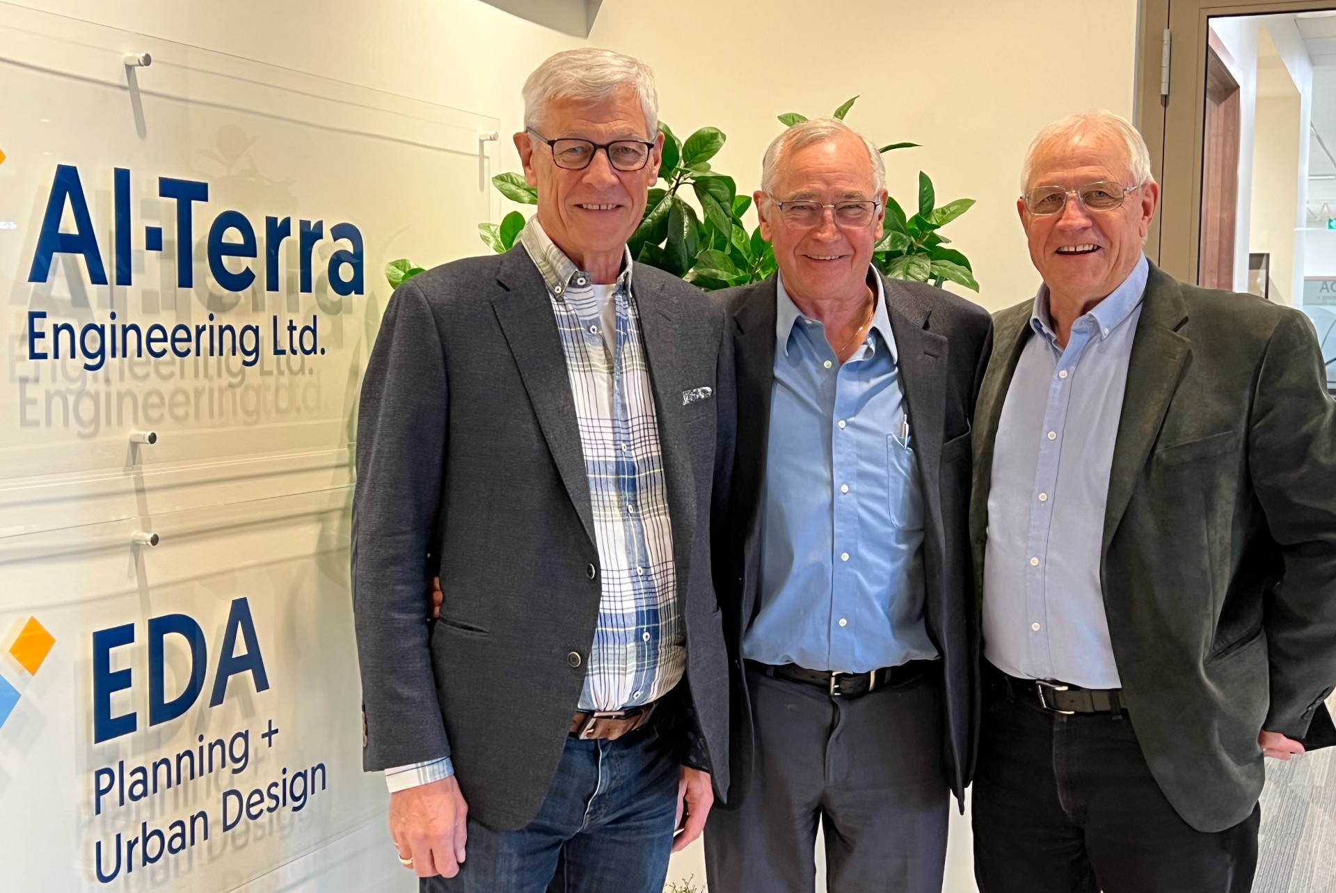 Civil engineers Leo, Corry and Martin Broks posing by an Al-Terra Engineering LTD sign in an office. 