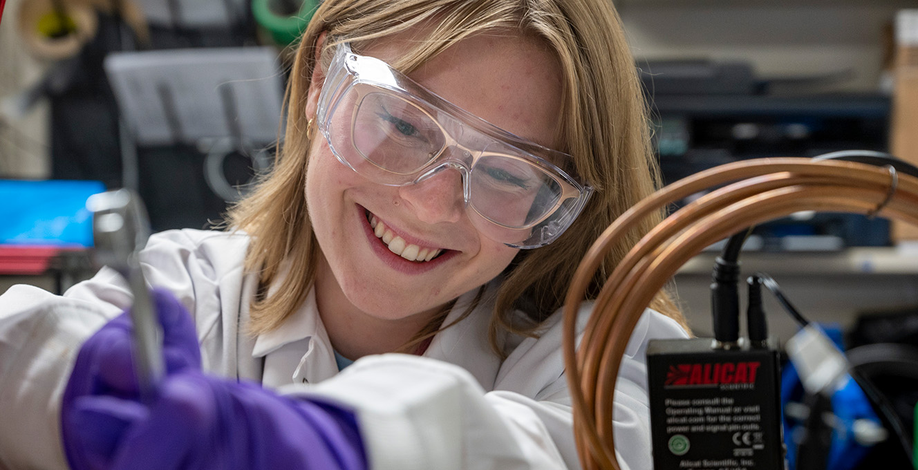 A graduate research student examines material in a lab.