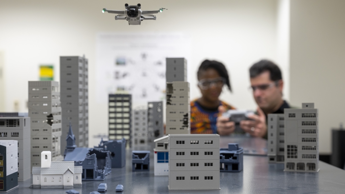 A man and woman flying a drone over a model city