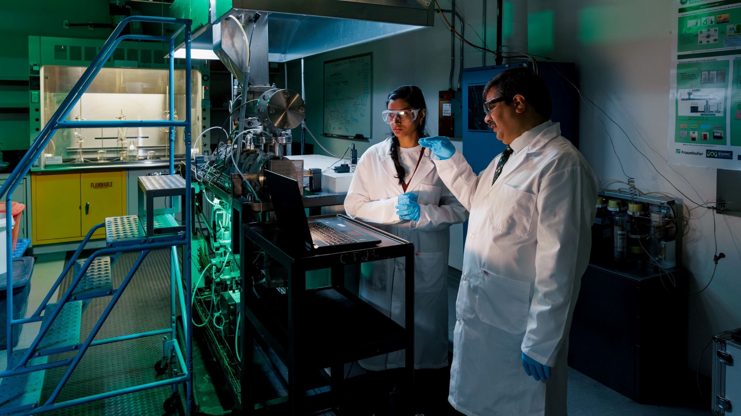 A professor and student in a lab staring at a laptop