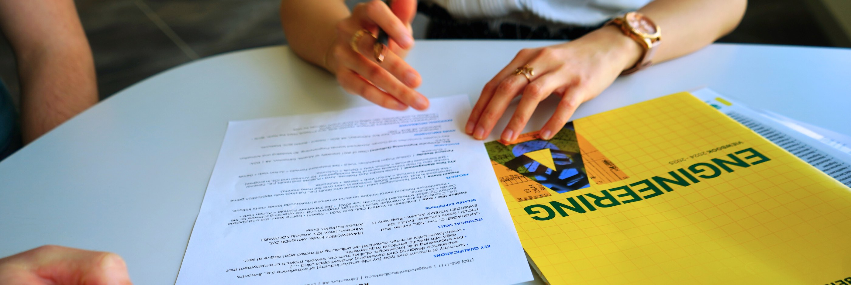 Group of people around a table helping a co-op student with a resume