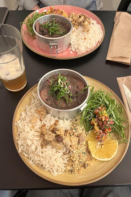 Feijoada, a black bean and meat stew, with a side of rice, salad, and flavoured crumbled bread
