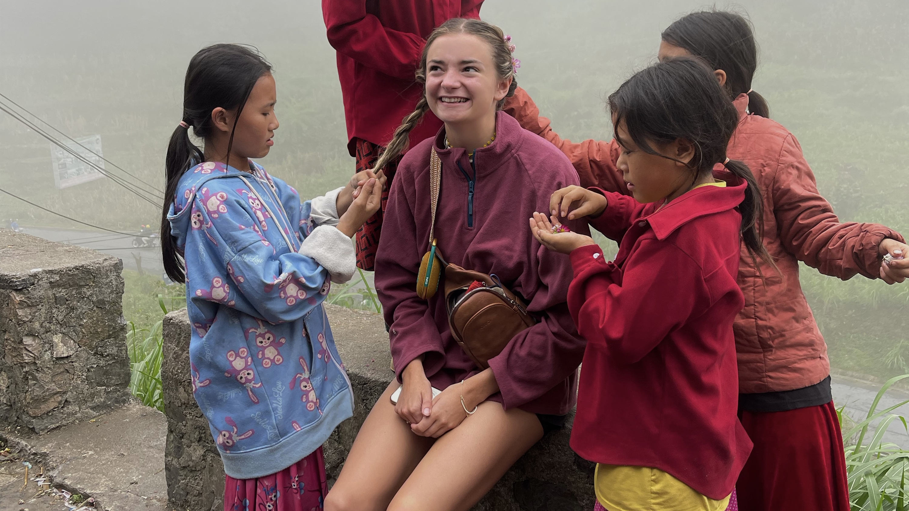 Larissa getting her hair braided by children