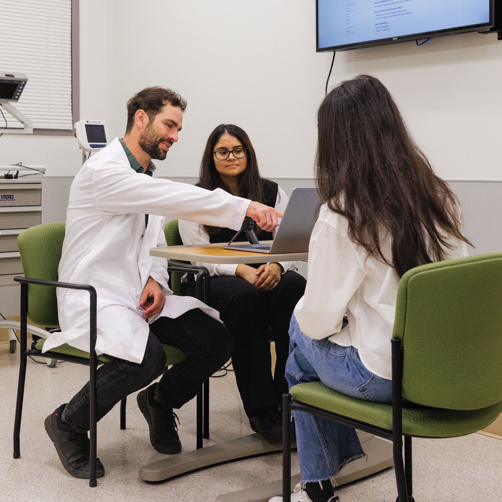 Three researchers from the AI and Health Hub discussing around a table with a laptop