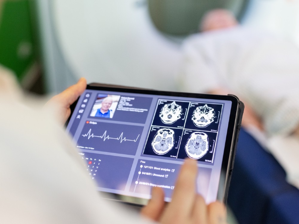 A person going into a ct scan and a person using an tablet to view results. 