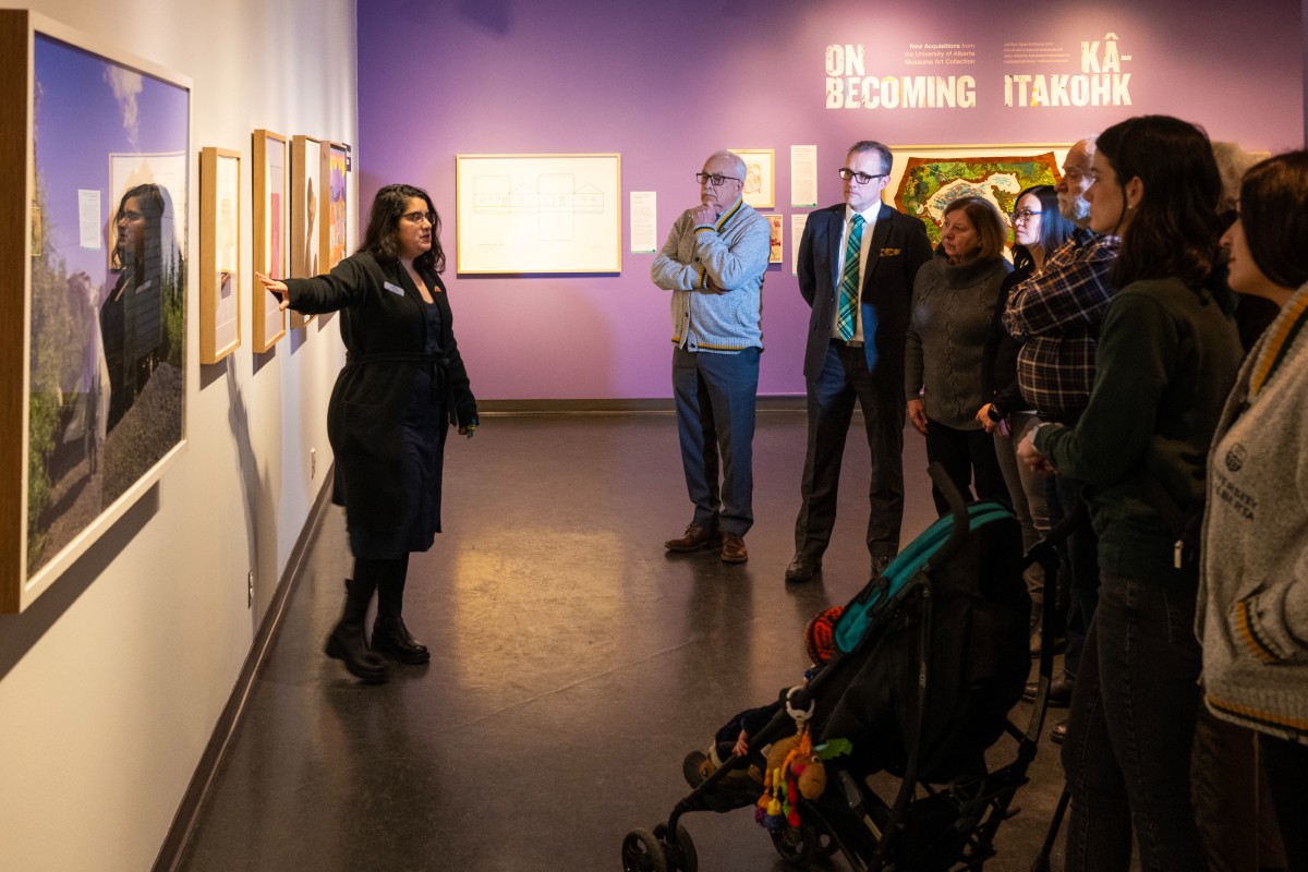 A woman doing a tour and pointing to artwork