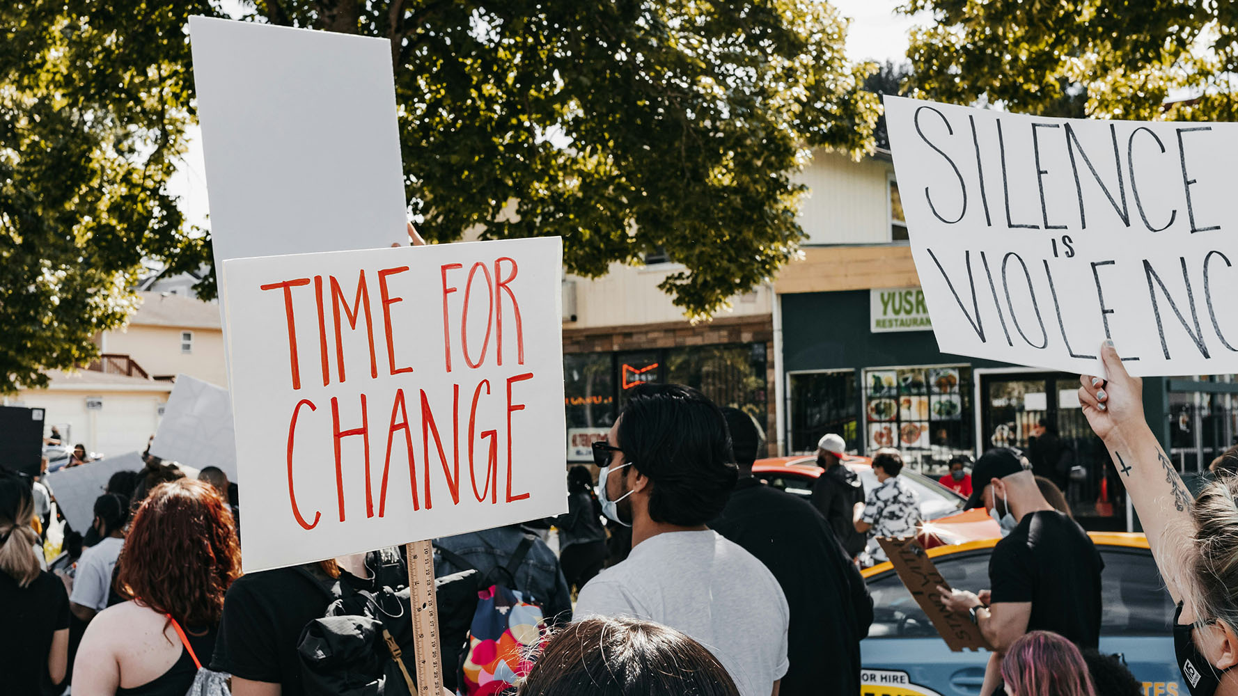 People at a rally with banners reading Time for Change and Silence is Violence