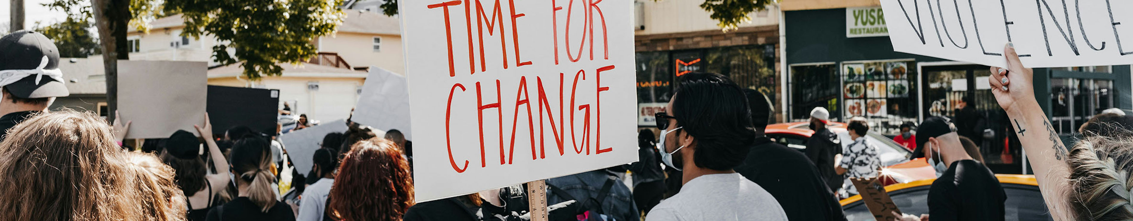 People at a rally with banners reading Time for Change and Silence is Violence