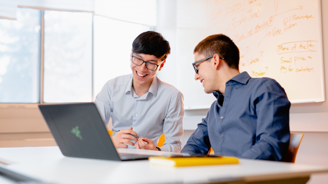 Two people smiling and looking at laptop