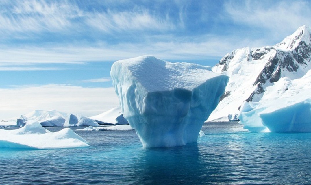 Ice berg floating in arctic ocean surrounded by ice caps