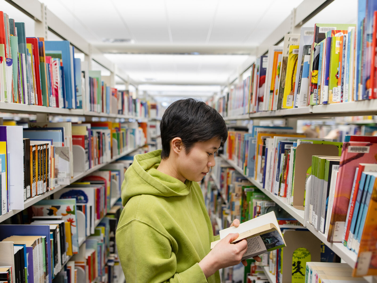 An individual looks through a book in one of the aisles of the U of A libraries.